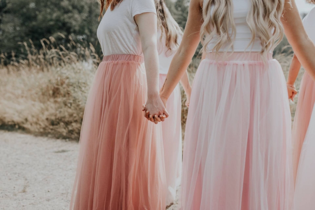 ピンク色のドレスを着た女性たちが手を取り合っている