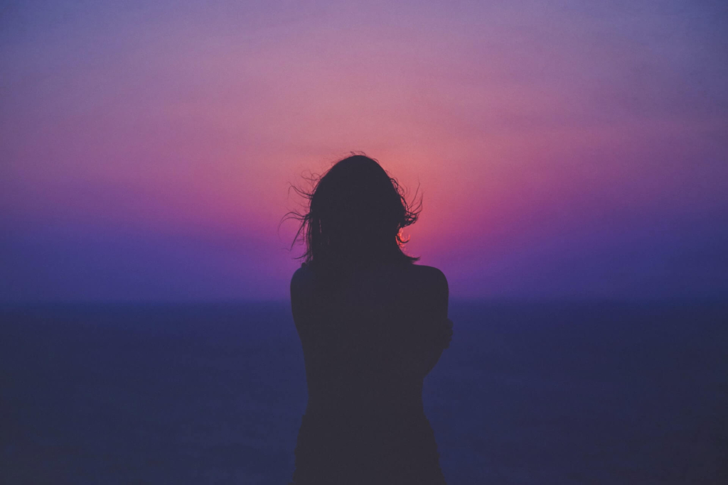 紫色の朝焼けの空と女性のシルエット