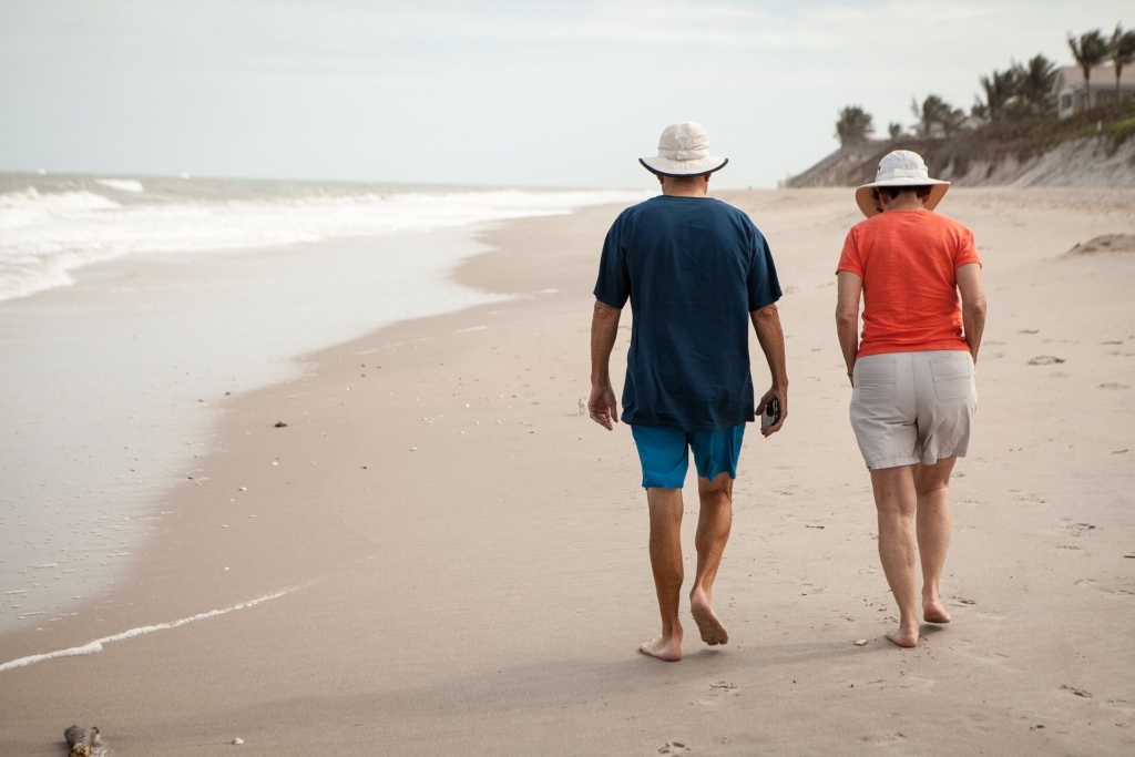 海辺を裸足で歩く夫婦